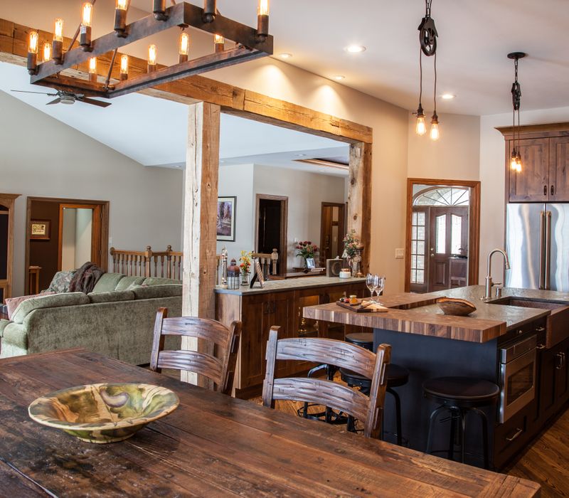 Rustic brick walls, rough-hewn beams, an end-grain cutting board, and a hammered copper sink and range hood add texture to this woodsy open concept kitchen.