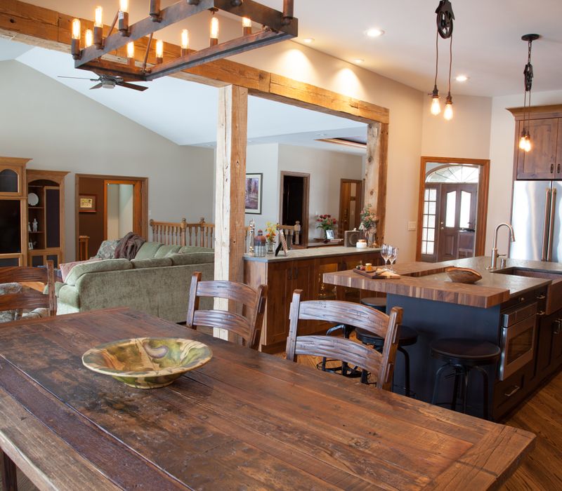 Rustic brick walls, rough-hewn beams, an end-grain cutting board, and a hammered copper sink and range hood add texture to this woodsy open concept kitchen.