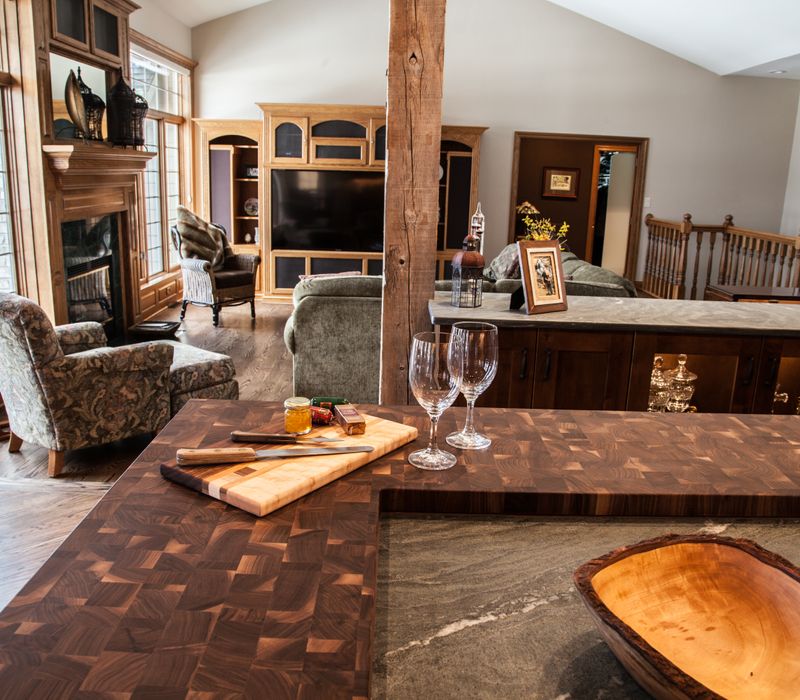 Rustic brick walls, rough-hewn beams, an end-grain cutting board, and a hammered copper sink and range hood add texture to this woodsy open concept kitchen.