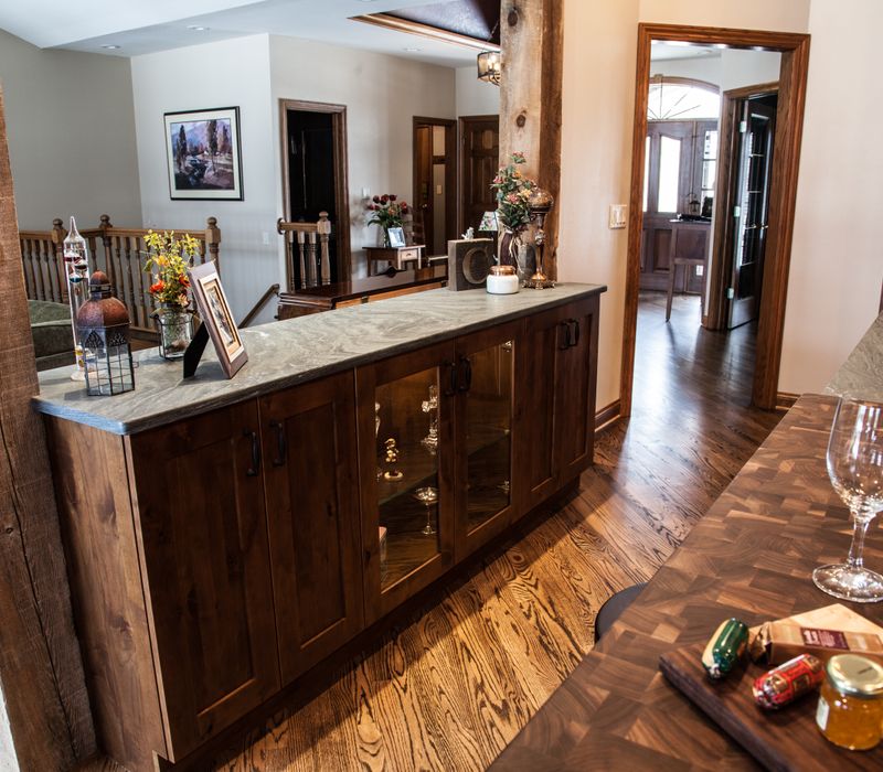 Rustic brick walls, rough-hewn beams, an end-grain cutting board, and a hammered copper sink and range hood add texture to this woodsy open concept kitchen.