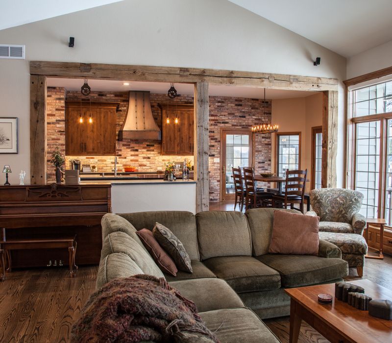 Rustic brick walls, rough-hewn beams, an end-grain cutting board, and a hammered copper sink and range hood add texture to this woodsy open concept kitchen.