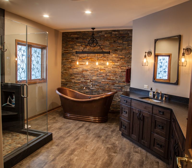 Rustic brick walls, rough-hewn beams, an end-grain cutting board, and a hammered copper sink and range hood add texture to this woodsy open concept kitchen.