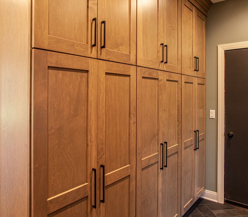 This warm, inviting kitchen features modern brushed gold chandeliers, marble countertops with gold veins, an end-grain cutting board, a metallic glass tile backsplash, and a black range hood with brass accents.