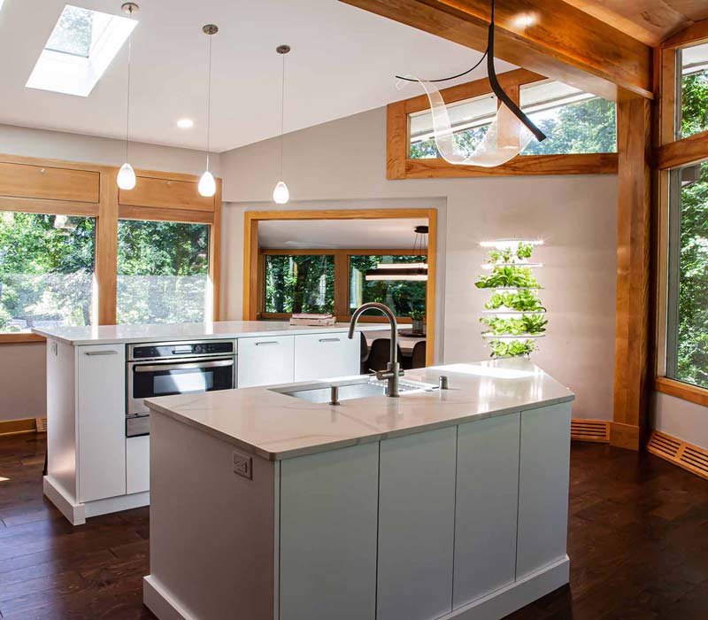 This kitchen remodel celebrates family, nature, and the unique geometry of the original home. It features crisp white cabinetry, cool-toned quartz countertops, two islands, and bold blue accents, plus a tactile mix of materials—wood, metal, glass, and stone—selected to stand the test of time in both durability and style.