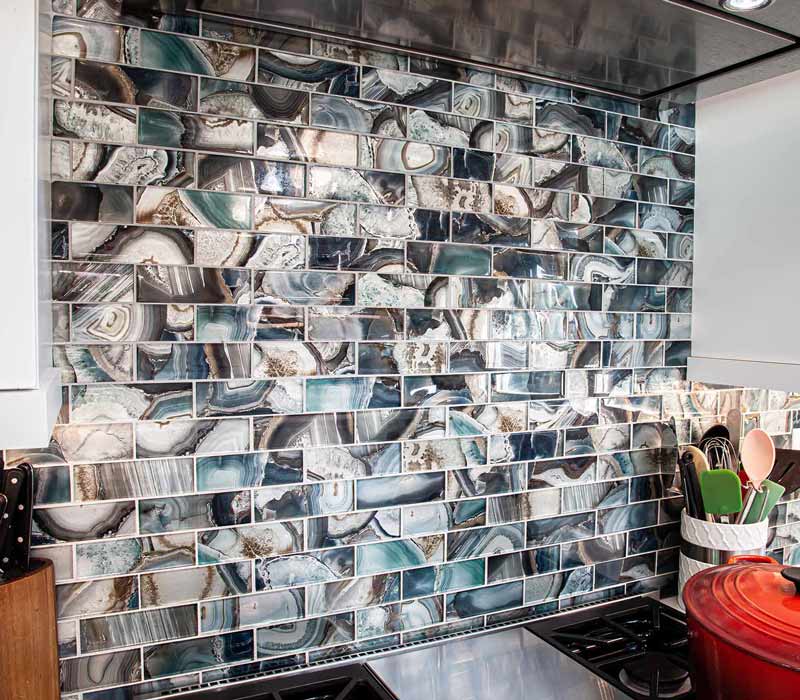 This kitchen remodel celebrates family, nature, and the unique geometry of the original home. It features crisp white cabinetry, cool-toned quartz countertops, two islands, and bold blue accents, plus a tactile mix of materials—wood, metal, glass, and stone—selected to stand the test of time in both durability and style.