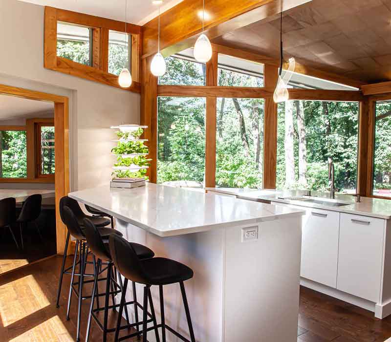 This kitchen remodel celebrates family, nature, and the unique geometry of the original home. It features crisp white cabinetry, cool-toned quartz countertops, two islands, and bold blue accents, plus a tactile mix of materials—wood, metal, glass, and stone—selected to stand the test of time in both durability and style.