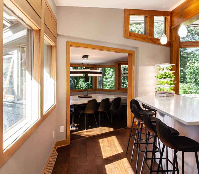 This kitchen remodel celebrates family, nature, and the unique geometry of the original home. It features crisp white cabinetry, cool-toned quartz countertops, two islands, and bold blue accents, plus a tactile mix of materials—wood, metal, glass, and stone—selected to stand the test of time in both durability and style.