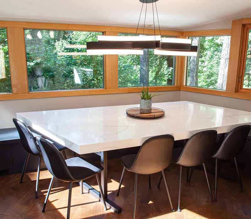 This kitchen remodel celebrates family, nature, and the unique geometry of the original home. It features crisp white cabinetry, cool-toned quartz countertops, two islands, and bold blue accents, plus a tactile mix of materials—wood, metal, glass, and stone—selected to stand the test of time in both durability and style.