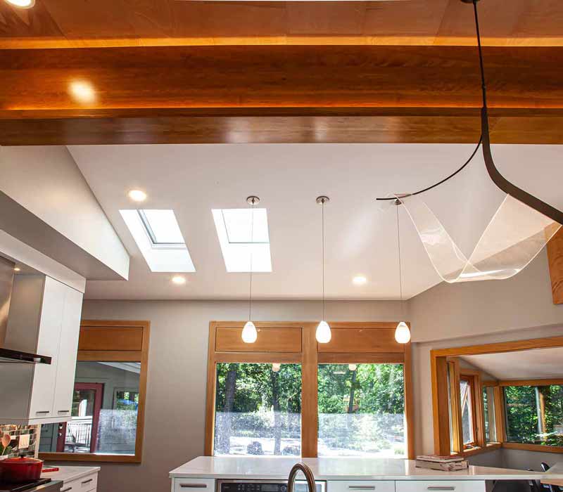 This kitchen remodel celebrates family, nature, and the unique geometry of the original home. It features crisp white cabinetry, cool-toned quartz countertops, two islands, and bold blue accents, plus a tactile mix of materials—wood, metal, glass, and stone—selected to stand the test of time in both durability and style.