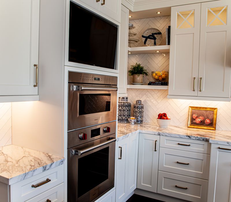 This light-filled, European inspired kitchen includes a bay windowed breakfast nook and opens onto an expansive deck. The striking black cabinetry coordinates with the black and brass pendant lamps and range hood.