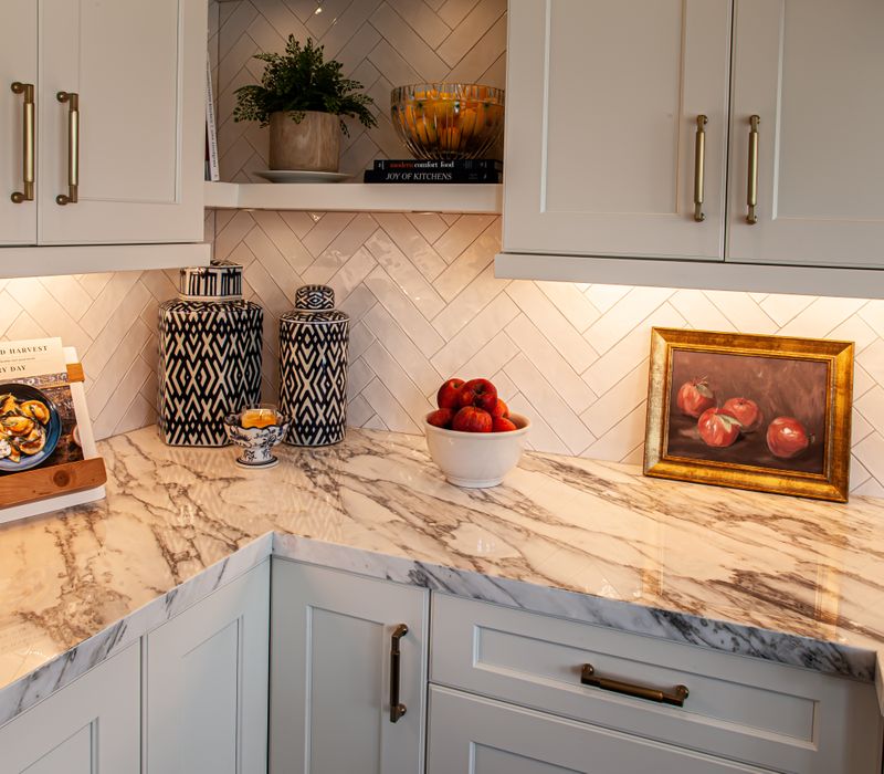 This light-filled, European inspired kitchen includes a bay windowed breakfast nook and opens onto an expansive deck. The striking black cabinetry coordinates with the black and brass pendant lamps and range hood.