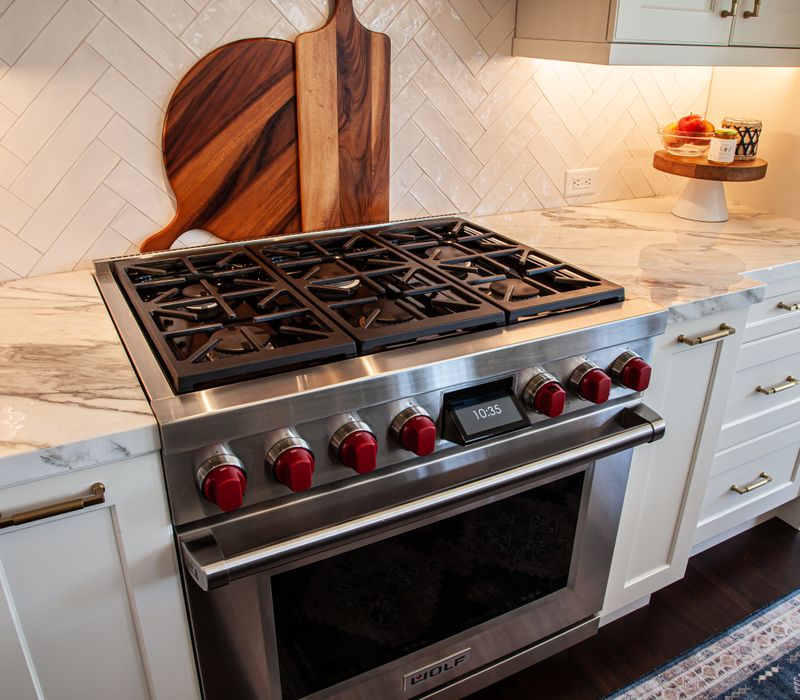 This light-filled, European inspired kitchen includes a bay windowed breakfast nook and opens onto an expansive deck. The striking black cabinetry coordinates with the black and brass pendant lamps and range hood.