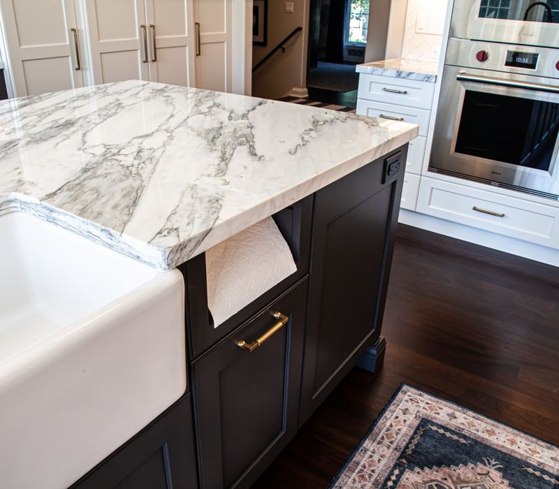 This light-filled, European inspired kitchen includes a bay windowed breakfast nook and opens onto an expansive deck. The striking black cabinetry coordinates with the black and brass pendant lamps and range hood.