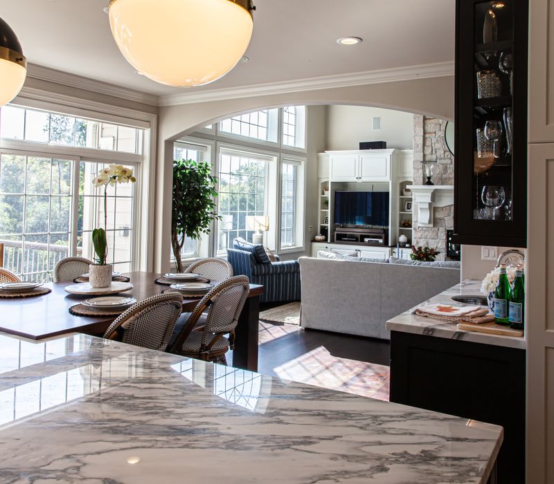 This light-filled, European inspired kitchen includes a bay windowed breakfast nook and opens onto an expansive deck. The striking black cabinetry coordinates with the black and brass pendant lamps and range hood.