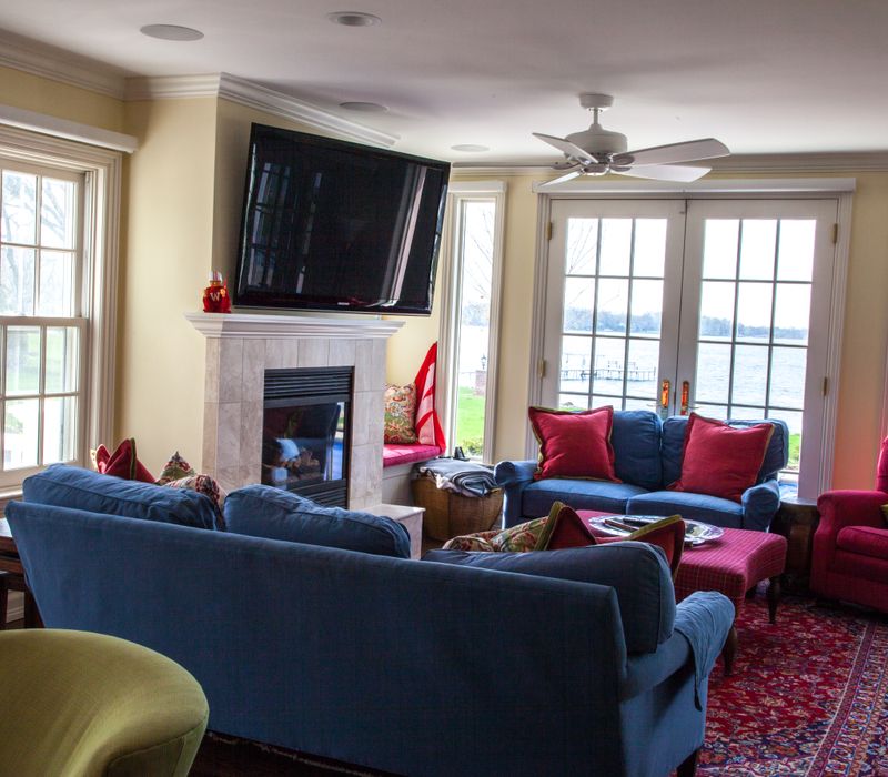 Hardwood floors, polished stone countertops, a mosaic stone tile backsplash, white glass-front cabinetry, and glass pendant lanterns combine in this spacious kitchen.