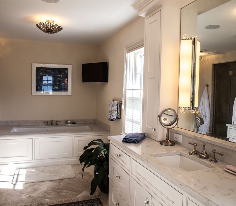 Hardwood floors, polished stone countertops, a mosaic stone tile backsplash, white glass-front cabinetry, and glass pendant lanterns combine in this spacious kitchen.