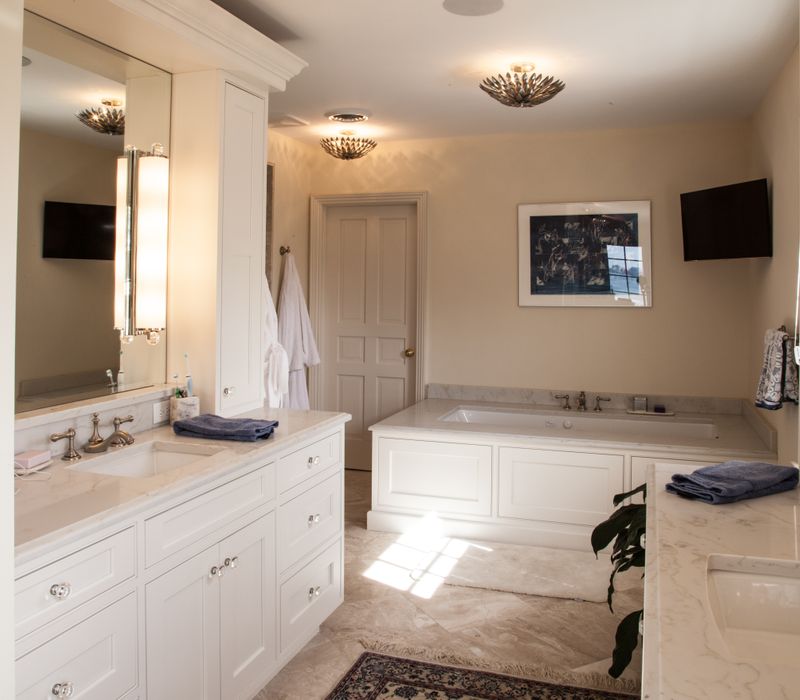 Hardwood floors, polished stone countertops, a mosaic stone tile backsplash, white glass-front cabinetry, and glass pendant lanterns combine in this spacious kitchen.