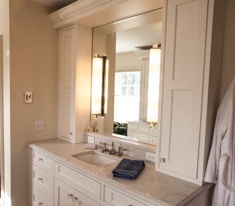 Hardwood floors, polished stone countertops, a mosaic stone tile backsplash, white glass-front cabinetry, and glass pendant lanterns combine in this spacious kitchen.