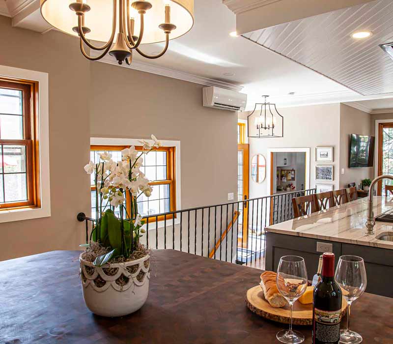 A kitchen featuring end-grain countertop, hardwood floors, and white glass tiles opens out onto a spacious deck in this Tudor style house.