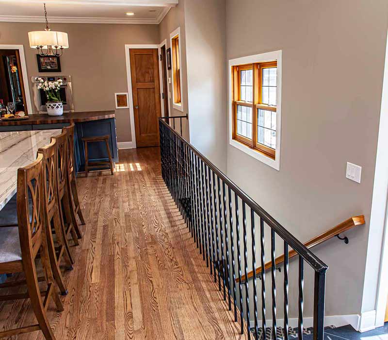 A kitchen featuring end-grain countertop, hardwood floors, and white glass tiles opens out onto a spacious deck in this Tudor style house.