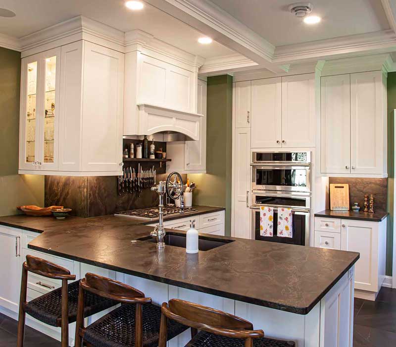 A chrome pull-down wheel faucet is the centerpiece of this traditional kitchen with natural slate countertops, art nouveau floral wallpaper, and green walls.