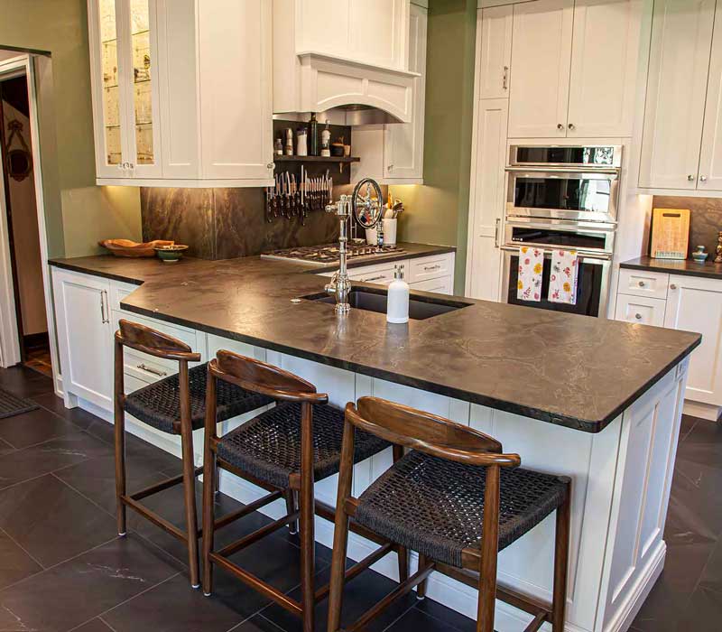 A chrome pull-down wheel faucet is the centerpiece of this traditional kitchen with natural slate countertops, art nouveau floral wallpaper, and green walls.