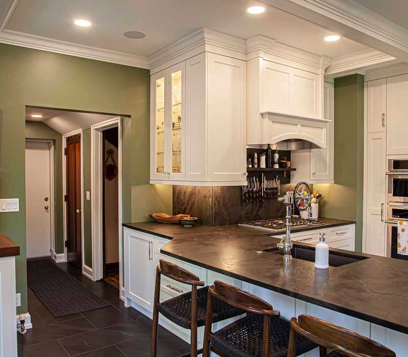 A chrome pull-down wheel faucet is the centerpiece of this traditional kitchen with natural slate countertops, art nouveau floral wallpaper, and green walls.