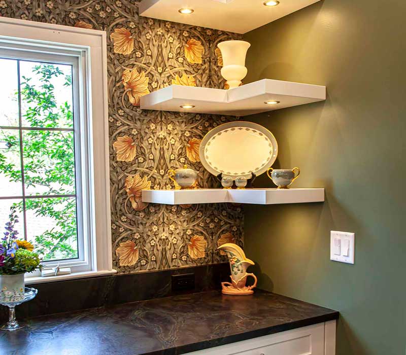 A chrome pull-down wheel faucet is the centerpiece of this traditional kitchen with natural slate countertops, art nouveau floral wallpaper, and green walls.