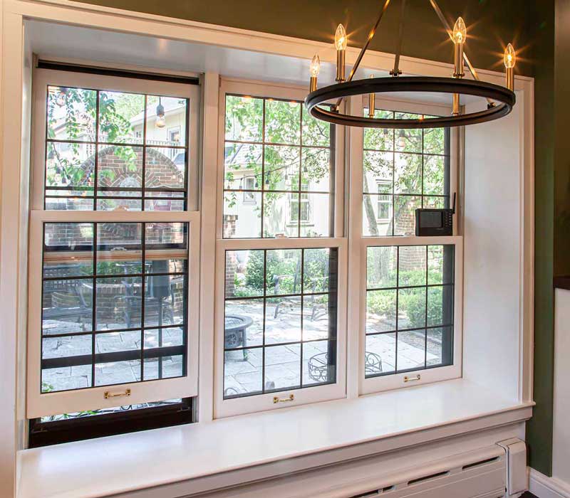 A chrome pull-down wheel faucet is the centerpiece of this traditional kitchen with natural slate countertops, art nouveau floral wallpaper, and green walls.