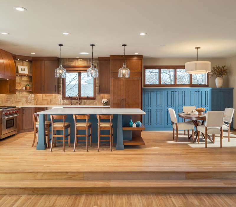 This whole-house remodel features a prairie-style kitchen adorned with custom cabinetry by DHDK, a primary suite with custom alder armoire, and bathroom with iridescent blue-green tiles.