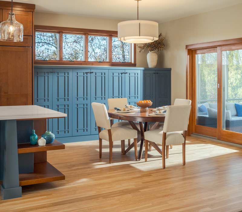 This whole-house remodel features a prairie-style kitchen adorned with custom cabinetry by DHDK, a primary suite with custom alder armoire, and bathroom with iridescent blue-green tiles.
