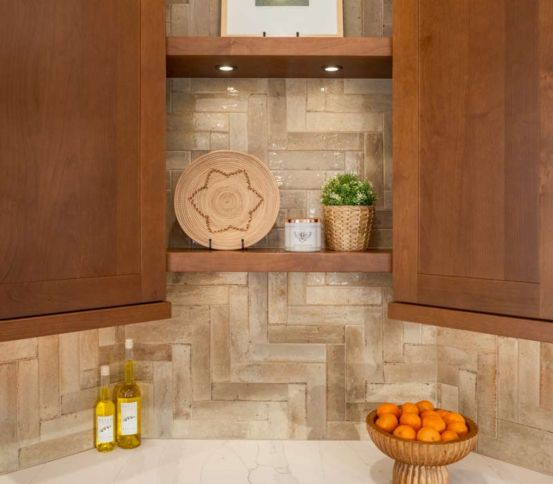 This whole-house remodel features a prairie-style kitchen adorned with custom cabinetry by DHDK, a primary suite with custom alder armoire, and bathroom with iridescent blue-green tiles.