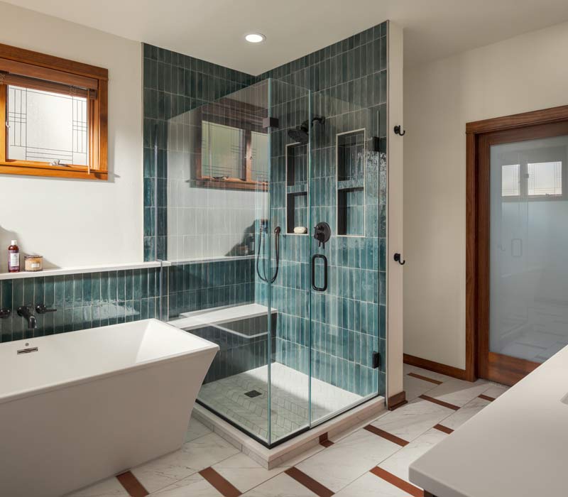 This whole-house remodel features a prairie-style kitchen adorned with custom cabinetry by DHDK, a primary suite with custom alder armoire, and bathroom with iridescent blue-green tiles.