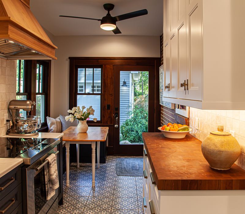 Dark woodwork, patterned terra cotta tile floors, and exposed brick interior walls define the kitchen and addition of this Craftsman home.