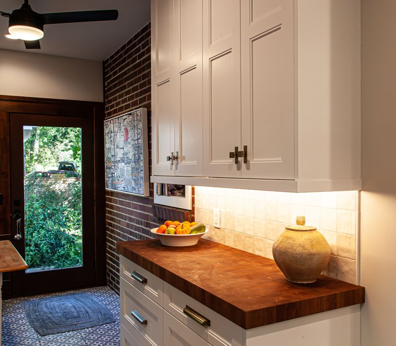 Dark woodwork, patterned terra cotta tile floors, and exposed brick interior walls define the kitchen and addition of this Craftsman home.