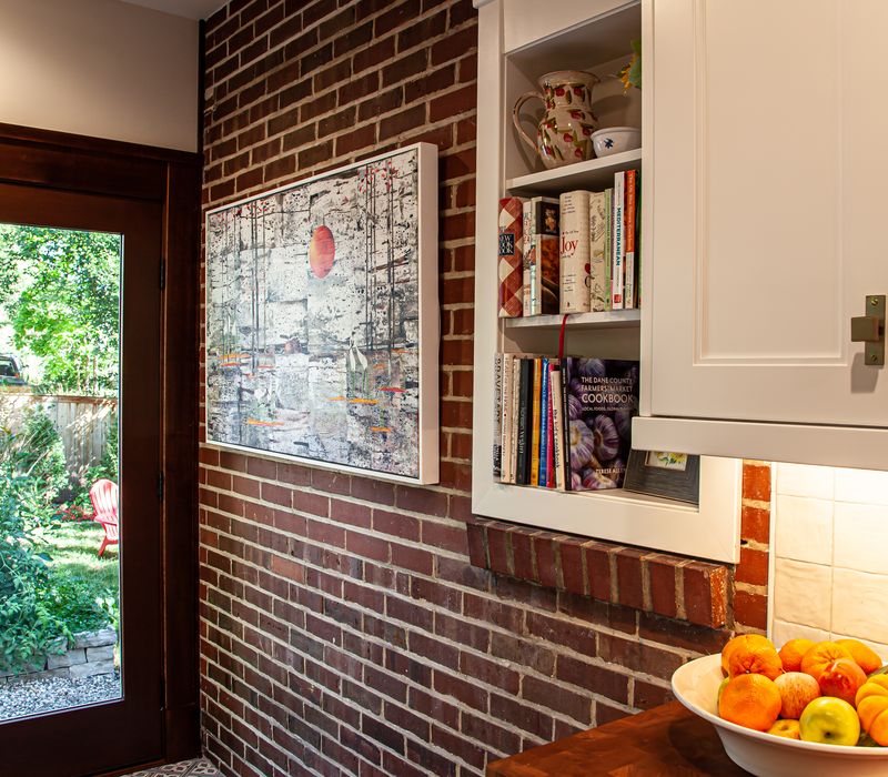 Dark woodwork, patterned terra cotta tile floors, and exposed brick interior walls define the kitchen and addition of this Craftsman home.