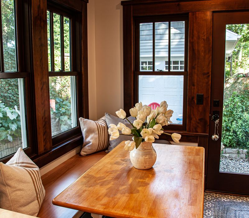 Dark woodwork, patterned terra cotta tile floors, and exposed brick interior walls define the kitchen and addition of this Craftsman home.