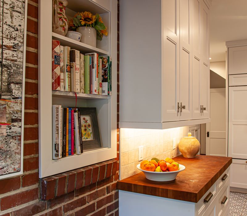 Dark woodwork, patterned terra cotta tile floors, and exposed brick interior walls define the kitchen and addition of this Craftsman home.