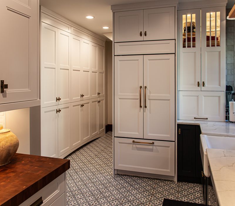 Dark woodwork, patterned terra cotta tile floors, and exposed brick interior walls define the kitchen and addition of this Craftsman home.