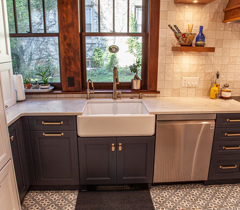 Dark woodwork, patterned terra cotta tile floors, and exposed brick interior walls define the kitchen and addition of this Craftsman home.