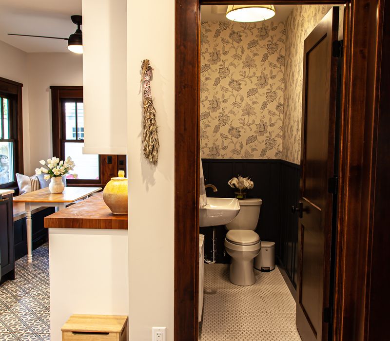 Dark woodwork, patterned terra cotta tile floors, and exposed brick interior walls define the kitchen and addition of this Craftsman home.