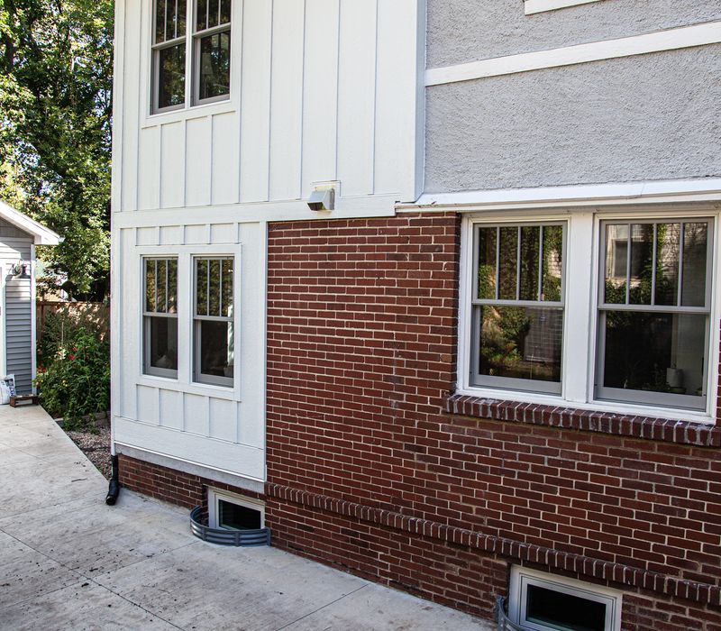 Dark woodwork, patterned terra cotta tile floors, and exposed brick interior walls define the kitchen and addition of this Craftsman home.