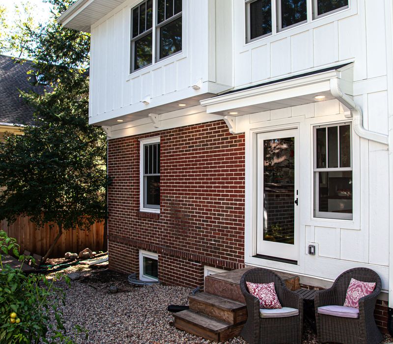Dark woodwork, patterned terra cotta tile floors, and exposed brick interior walls define the kitchen and addition of this Craftsman home.