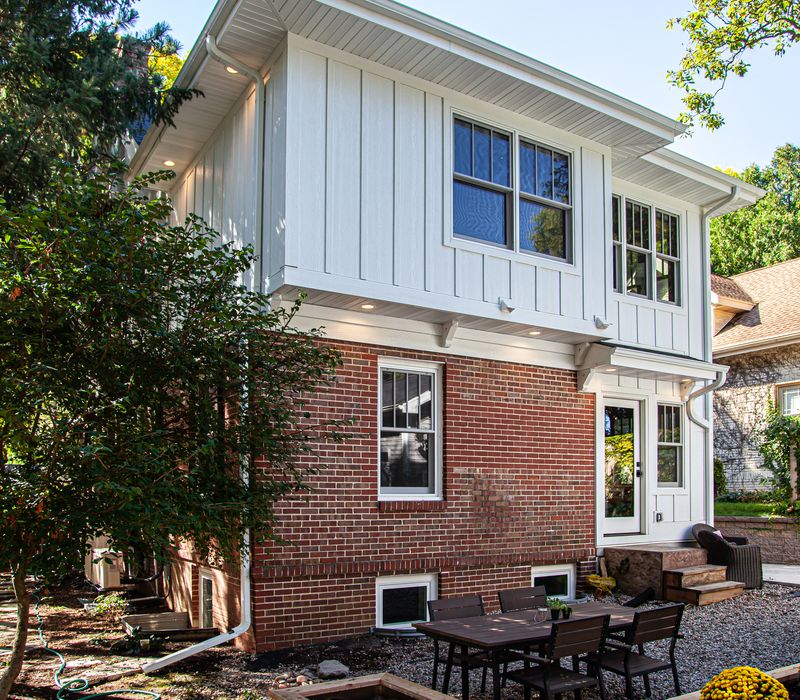 Dark woodwork, patterned terra cotta tile floors, and exposed brick interior walls define the kitchen and addition of this Craftsman home.