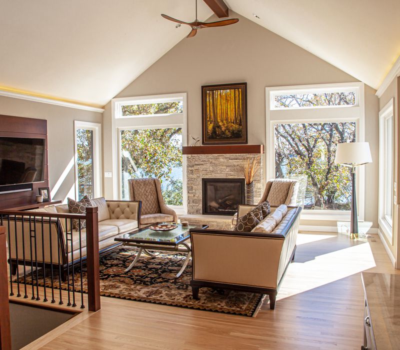 This lakeside brick home has vaulted and coffered ceilings, twin picture windows on either side of a fireplace, hardwood floors, two second-story decks, and a finished basement. 