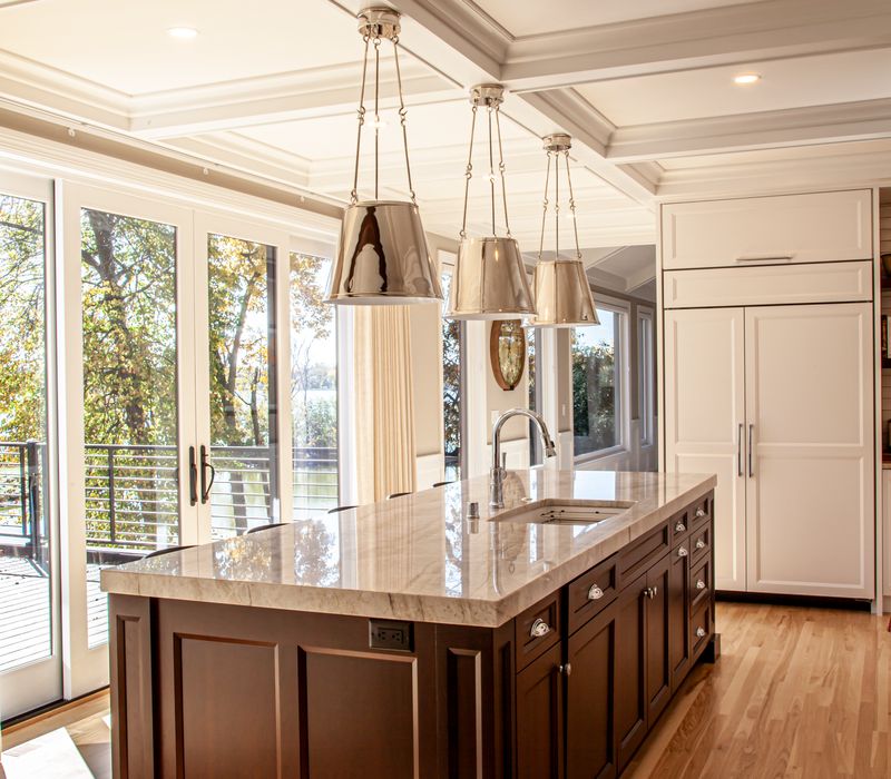 This lakeside brick home has vaulted and coffered ceilings, twin picture windows on either side of a fireplace, hardwood floors, two second-story decks, and a finished basement. 