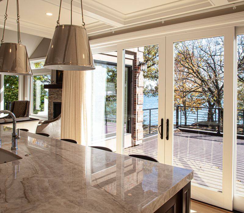 This lakeside brick home has vaulted and coffered ceilings, twin picture windows on either side of a fireplace, hardwood floors, two second-story decks, and a finished basement. 