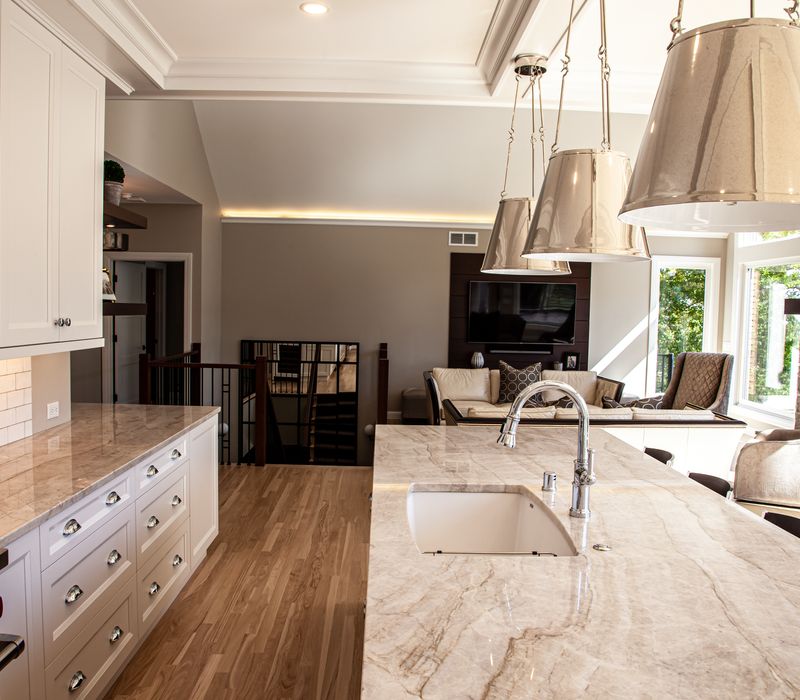 This lakeside brick home has vaulted and coffered ceilings, twin picture windows on either side of a fireplace, hardwood floors, two second-story decks, and a finished basement. 