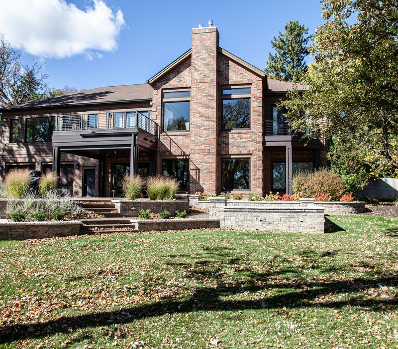 This lakeside brick home has vaulted and coffered ceilings, twin picture windows on either side of a fireplace, hardwood floors, two second-story decks, and a finished basement. 