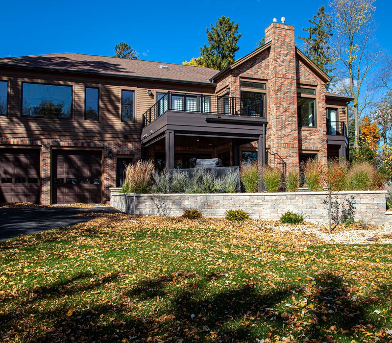 This lakeside brick home has vaulted and coffered ceilings, twin picture windows on either side of a fireplace, hardwood floors, two second-story decks, and a finished basement. 